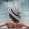 a person in a hat and swimsuit sitting in a pool